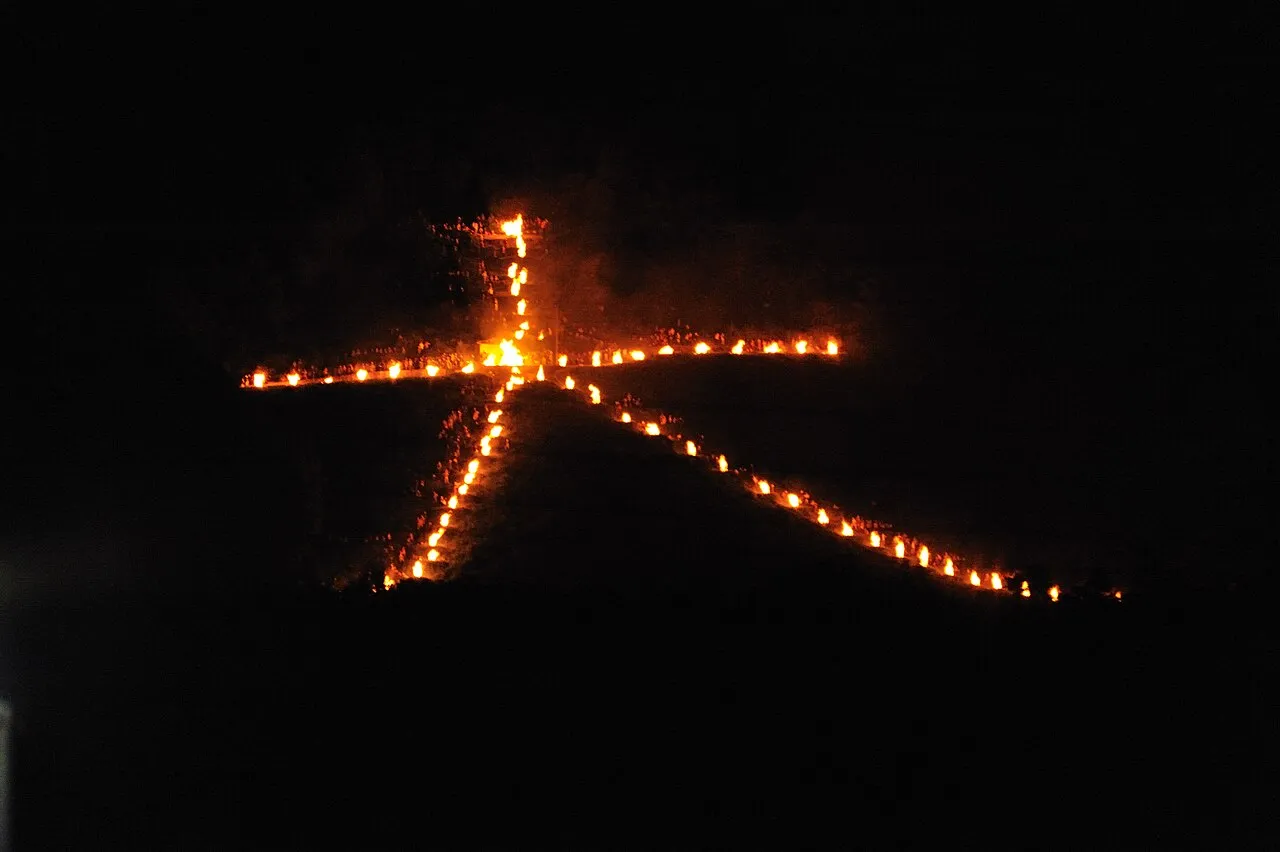 The character 大 burning in fire on a dark mountainside at night.