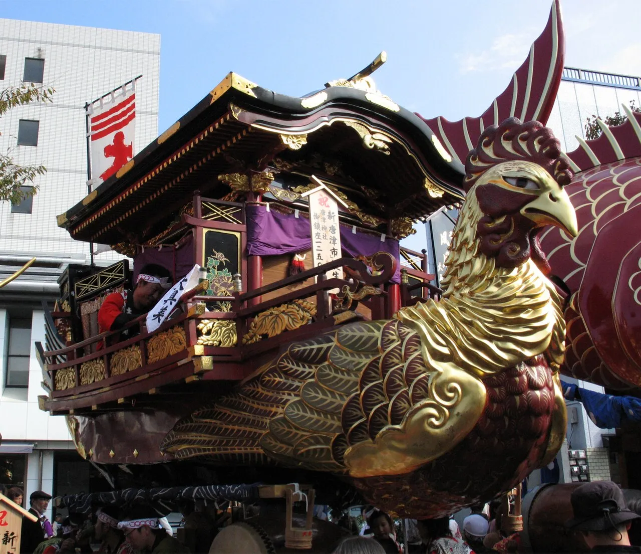 A float shaped like a ship with a golden phoenix head at the prow and a lacquered house on deck.