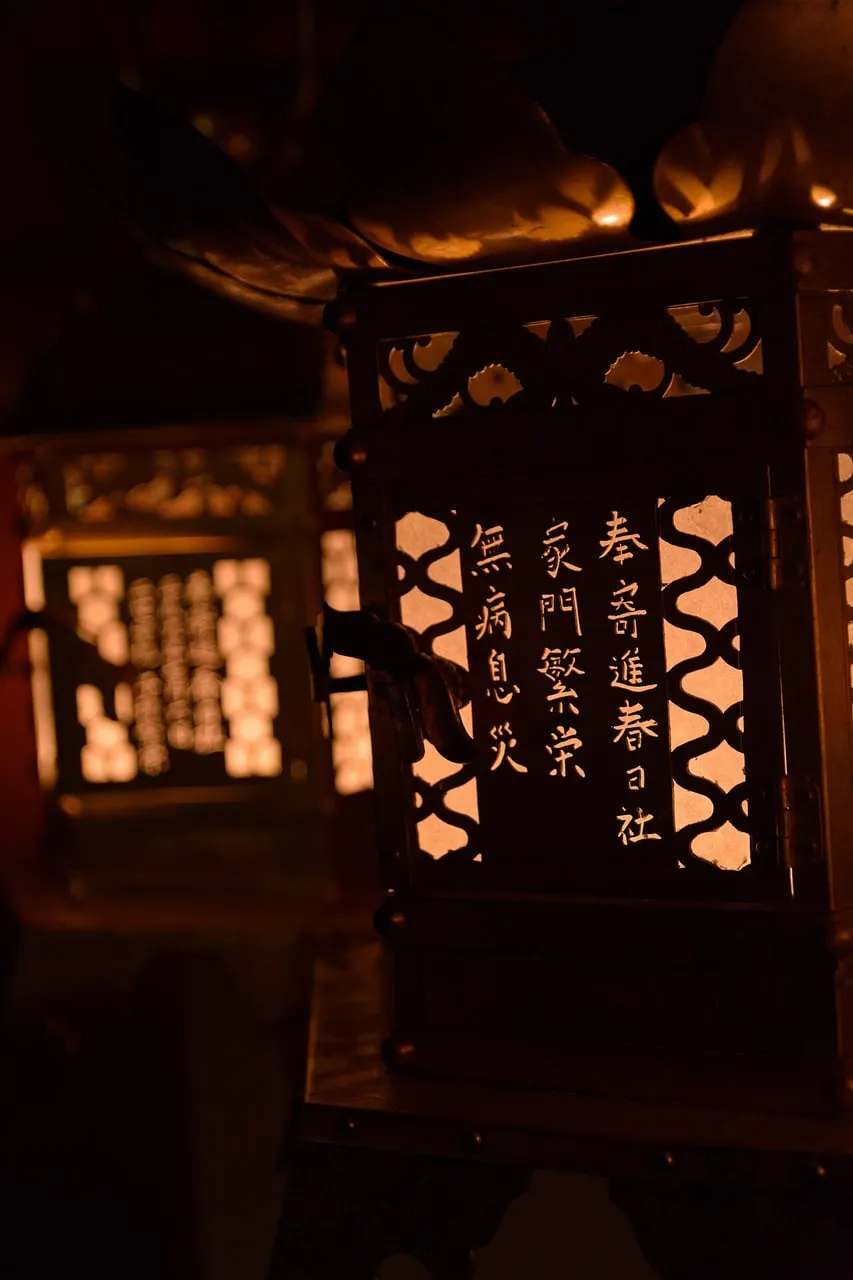 A lit lantern with inscribed paper panels glows in the dark.