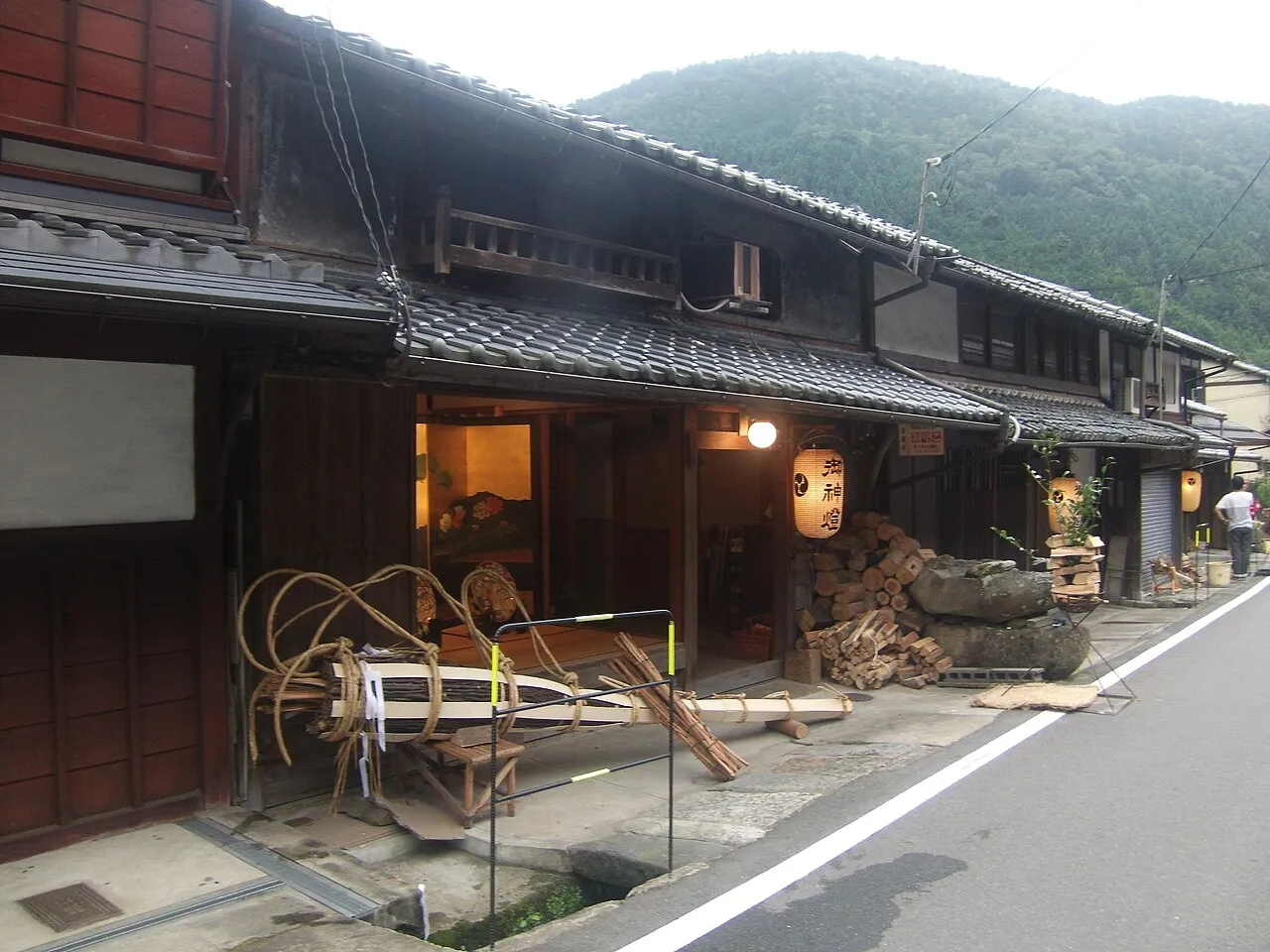 Large pine torches stand ready outside old wooden houses on the village street of Kurama.
