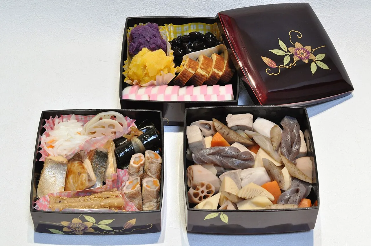 Three lacquered boxes filled with New Year dishes: black beans, rolled omelette, fish cake, sweet potato, simmered root vegetables and fish.